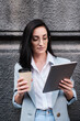 © Kostiantyn - serious businesswoman holding tablet and cofeein a urban background