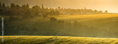 Fotomural panorama of a village situated among beautiful undulating fields on a beautiful misty morning