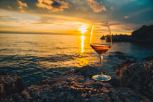 Glass Of Wine At Rocky Sea Beach On Sunset