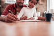 © bnenin - Low angle image of father and daughter sitting together and writing. Doing homework.