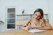 © bnenin - Focused young woman writing in paper notebook, portrait.