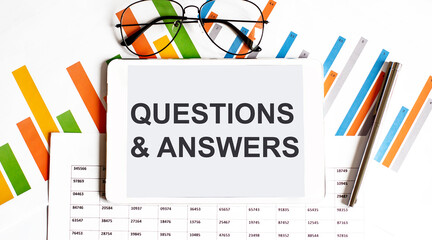 Poster - The tablet with text QUESTIONS & ANSWERS on business charts and pen