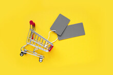 Mini Shopping Cart With Blank Gray Labels On A Yellow Background.