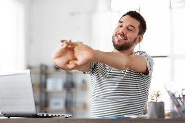 Poster - technology, remote job and business concept - happy smiling man with laptop computer stretching at home office