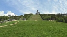 Zooming Aerial 4k Shot Of A Four Wheeler Driving Up A Green Slope Heading Towards The Sky Walk Attraction In Dolní Morava, Czechia With A Cableway And Forests Around. Fourwheeler Driving Uphill.