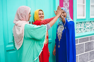 Young muslim girls stacking hands outdoor - Islamic happy women celebrating together - Youth, lifestyle, university, relationship, religion and friendship concept - Focus on hands