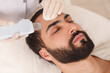 © mad_production - Close up of a handsome bearded man getting ultrasound cleanse by cosmetologist