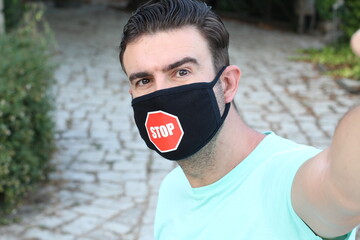 Wall Mural - Young man wearing protective face mask  with stop sign 