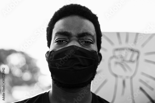 Young black man wearing face mask during equal rights protest - Concept of demonstrator on road for Black Lives Matter campaign - Focus on eyes - Black and white editing