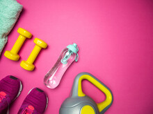 Dumbbells, Kettlebell, Training Shoes, Filtered Water Bottle And Towel. Fitness Flat Lay Composition With Copyspace On Pink Background.
