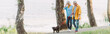 © LIGHTFIELD STUDIOS - Panoramic shot of smiling senior woman walking near husband and pug dog on leash in park