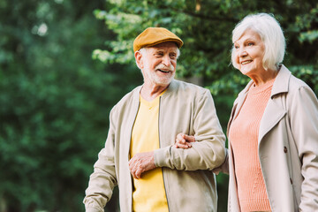 Elderly man smiling while looking at wife in park