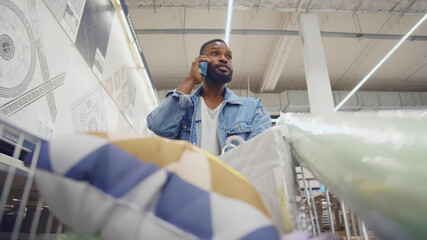 Wall Mural - Buyer afro man with shopping cart in hardware store talking on phone