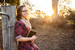 © Clare Seibel-Barnes/Austockphoto - Happy young writer holding pen and notebook leaning on fence post in paddock