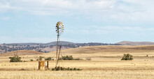 Windmill And Old Tank In Stubble With Rolling Hills