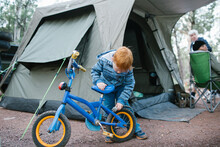 Young Boy Inspecting His Bike At A Camp Site