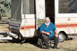 © Caro Telfer/Austockphoto - Grey haired man sitting in front of pop-up caravan
