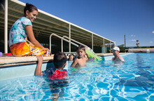 Family With Young Children In Swimming Pool