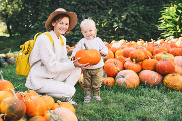 happy mother and child at pumpkin patch outdoors.
