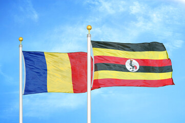 Romania and Uganda two flags on flagpoles and blue sky