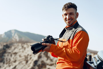 Young man traveler taking photos of mountains with professional camera