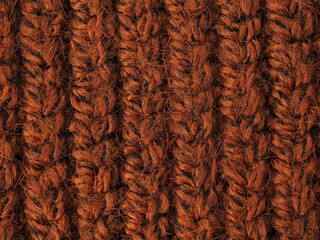 A beautiful closeup of a hand knitted warm and soft wool pattern. Texture of a brown sweater, socks or scarf . orange knitted material background