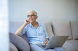 © Dragana Gordic - Shot of a smiling confident businesswoman using laptop and working at home. Beautiful mature woman sitting on couch and using laptop. Smiling lady browsing internet over tablet at home.