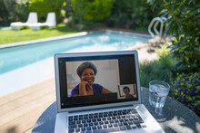 Women Video Conferencing On Laptop Screen At Sunny Poolside