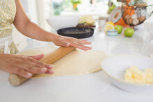 Woman Rolling Out Pie Dough With Rolling Pin On Kitchen Counter