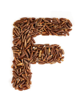 Letter F of the English alphabet made from brown rice on an isolated background.