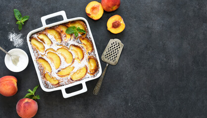 Wall Mural - Delicate cake with peaches sprinkled with powdered sugar on a black concrete background