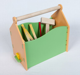 Carpenter wooden tool box on white backdrop. green and yellow wooden holder for instruments, pencil and ruler for kids. Close up photo.