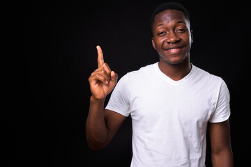 Wall Mural - Happy young handsome African man against black background