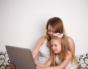 Poster - young mother works with her daughter on the pc at home