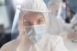 © Videophilia - A close-up of a female doctor or medical researcher wearing protective gear, mask and face shield in a laboratory.