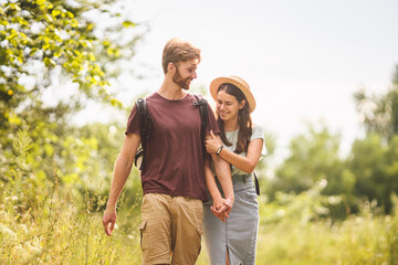 Couple Hiking Along Woodland Path. Happy loving man and woman on holiday walking together. Active lifestyle concept. Young people walking with backpacks on country road outdoors