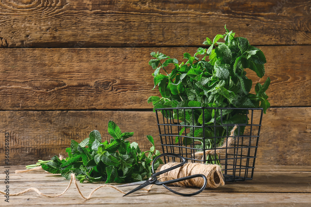 Fresh green mint, thread and scissors on wooden background