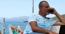 Portrait Of A Hispanic  Tourist Man On Luxury Yacht Talking On Phone  At Summer Vacation