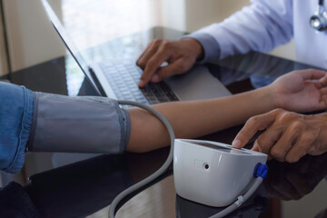 Doctor work on computer, measuring blood pressure for patient,