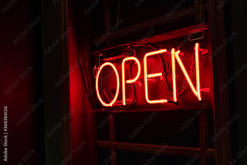Red neon OPEN sign at an angle in a window at the end of a dark and ...