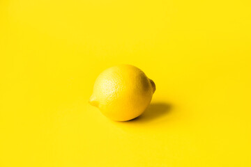 Wall Mural - One ripe lemon on a yellow background. Monochrome image. Minimal summer concept.