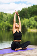 © Sergey Chayko - Girl on a wooden bridge near the river, practicing yoga asanas, performing the lotus position with hands raised up