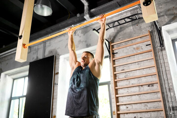 Poster - sport, fitness, exercising and people concept - man doing pull-ups on horizontal bar in gym