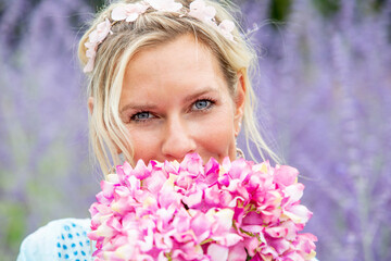 blond woman in her 40s standing in field of purple flowers