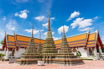 Ancient buddhist stupas and pagoda at Temple of Reclining Buddha (Wat Pho) with blue sky in Bangkok city, Thailand