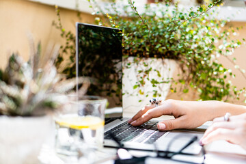 Woman's hands on laptop keyboard, cozy workplace