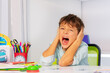 Screaming sad boy with autistic disorder cover ears and scream during development therapy class lesson