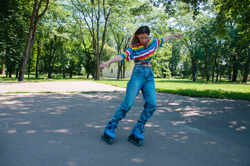 Beautiful teenager girl has fun rollerblading in the park, performs tricks