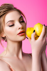 Wall Mural - beautiful blonde woman with closed eyes holding ripe lemons isolated on pink