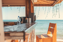 Sunny. An Empty Bar Counter And An Empty Chair Against The Background Of The Beach And The Sea. Vacation And Summer
